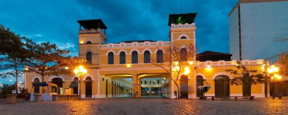 Fachada amarilla iluminada del Mercado Público de Florianópolis al anochecer.
