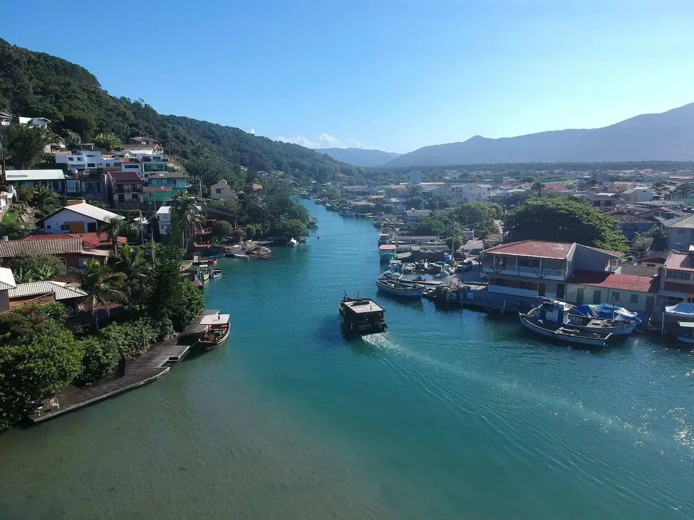 Pueblo a la orilla del canal de la Barra da Lagoa, en Florianópolis, con barcos de pesca.